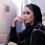 Elegant Middle Eastern woman in traditional fashion, sitting outdoors in Dubai.