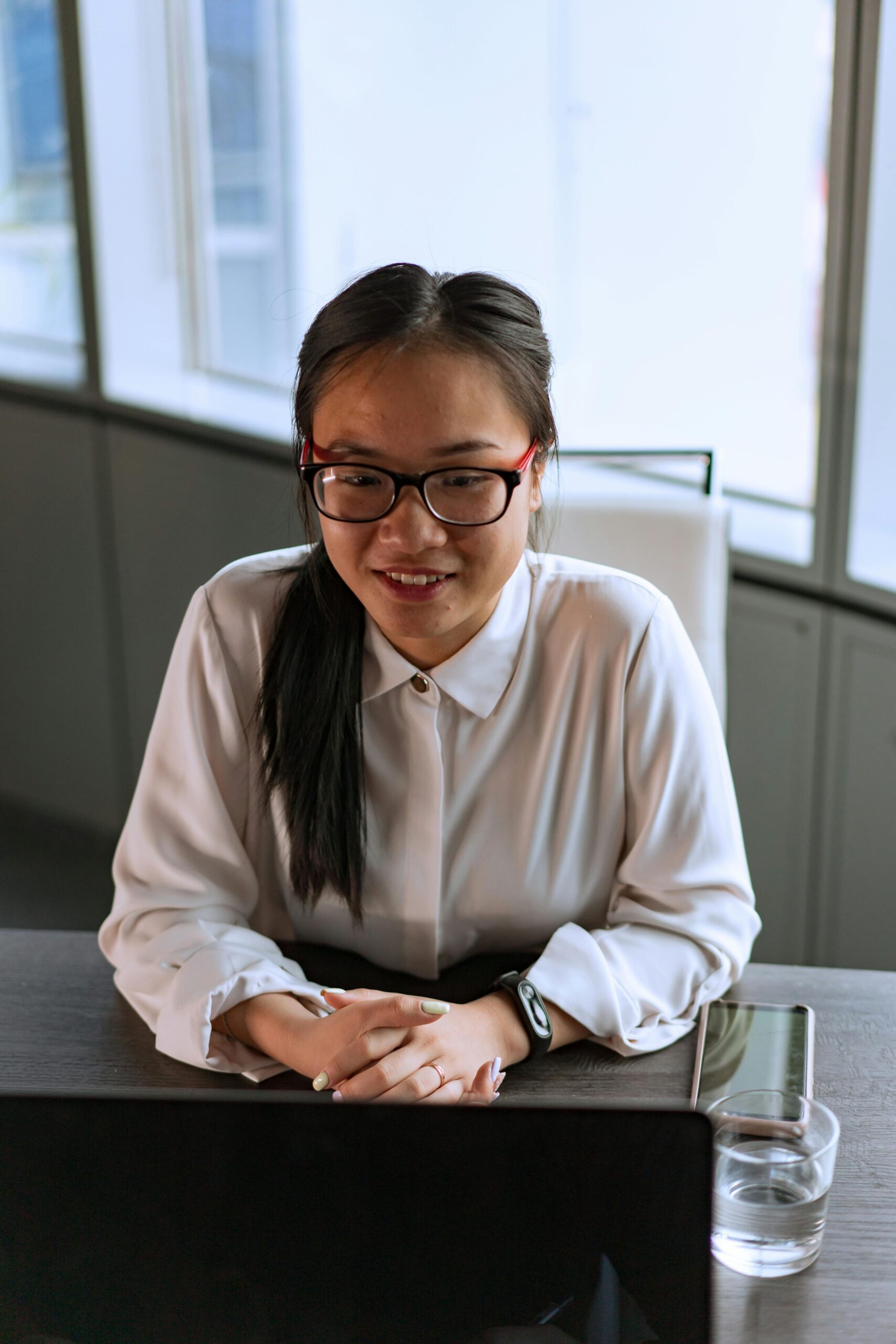 Asian woman working on a laptop in a modern office setting.